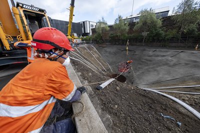 Crews spraying a concrete-like product on the slope of the hole which helps to prevent more material from falling in